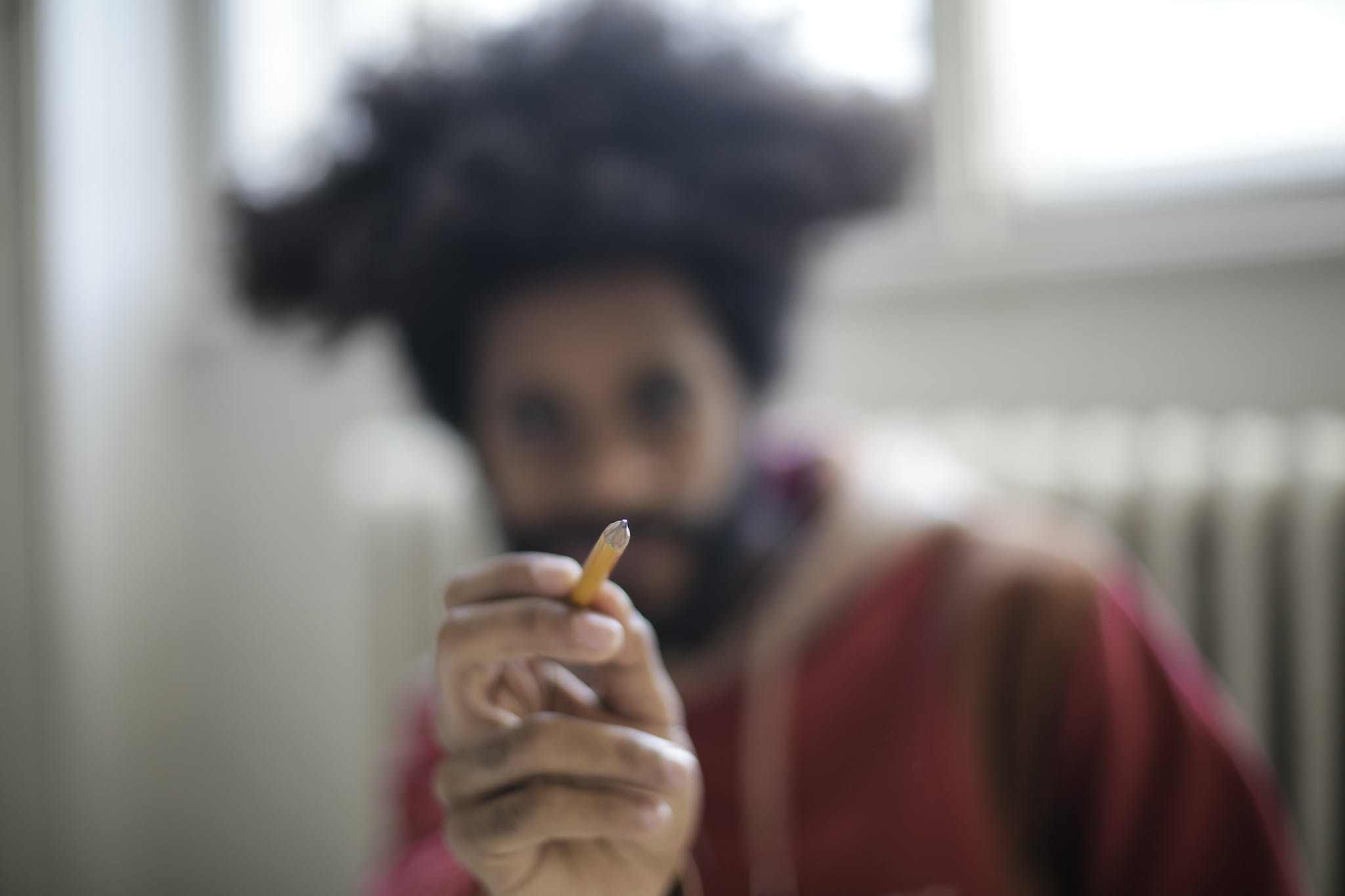 Eccentric young male artist showing pencil on blurred background being ready for painting and designing process as concept of imagination and fantasy